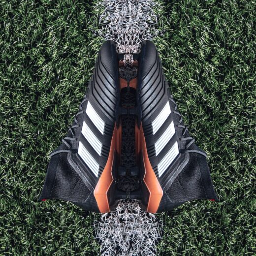 pair of black Adidas cleats on grass field